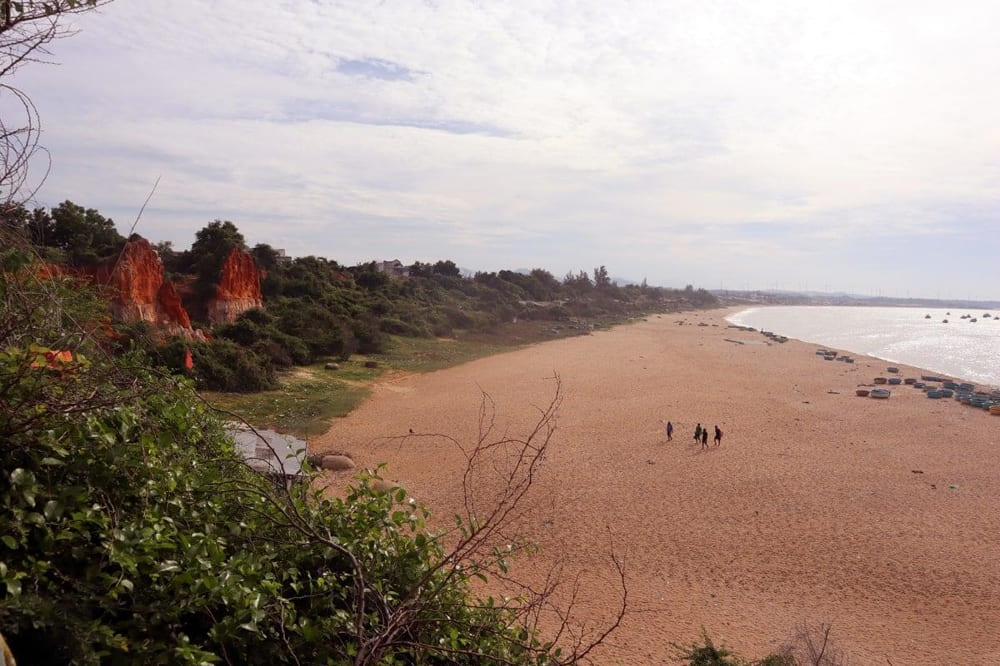 Ganh Son Beach showing the striking contrast between red sand dunes and blue ocean with traditional fishing villages
